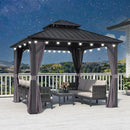 Grey hardtop gazebo with curtains, string lights, and outdoor furniture on a deck at night, patio shade solution.