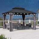 Grey hardtop gazebo with curtains, string lights, and outdoor furniture, patio shade solution at night