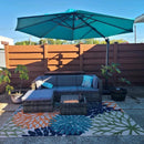 Cantilever patio umbrella providing shade over outdoor sectional sofa and coffee table, colorful floral rug.