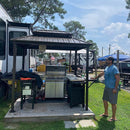 Bronze hardtop grill gazebo with BBQ and side shelves, ideal for outdoor cooking and entertaining on the patio.
