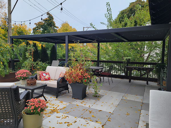 Cozy patio with pergola, string lights, seating, and plants.