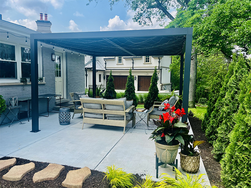 Patio with pergola, seating, flowers, and greenery.