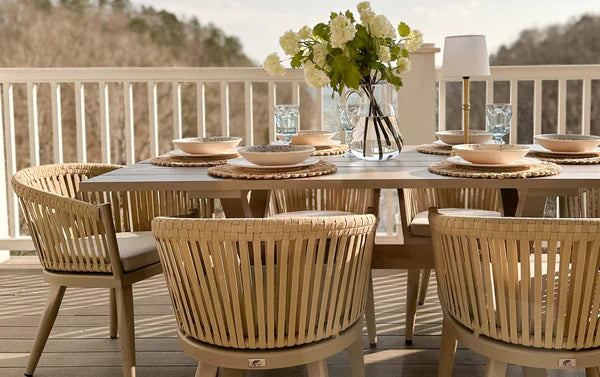 An outdoor dining set with a natural wood table and natural woven chairs