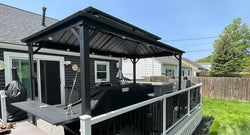 A modern grill gazebo with a sleek, matte black frame and slanted roof, featuring built-in LED lighting and a multi-functional side shelf, set in a stylish backyard patio.