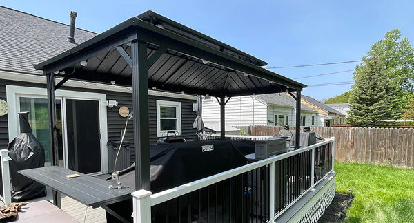 A modern grill gazebo with a sleek, matte black frame and slanted roof, featuring built-in LED lighting and a multi-functional side shelf, set in a stylish backyard patio.