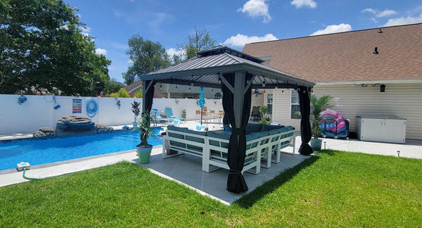 Black metal gazebo with curtains over a white outdoor dining set beside a swimming pool in a backyard