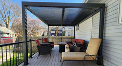 A pergola with open slatted roof over a patio, featuring a table and chairs with a scenic mountain view.