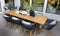 Modern outdoor dining set with wooden table and black rope chairs on a deck, featuring decorative black vases and white accents, with large glass windows in the background