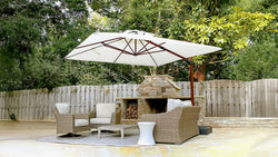 Outdoor seating area with white umbrella, wicker chairs, and stone fireplace