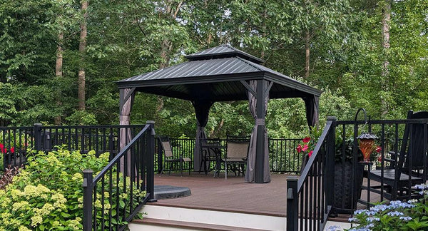 Outdoor hardtop gazebo on deck surrounded by greenery