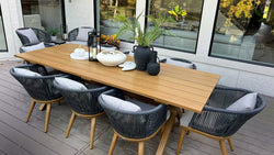 An outdoor dining set with a wooden table and woven chairs, adorned with decorative items and plants.