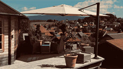 Large cantilever patio umbrella over a deck with outdoor furniture