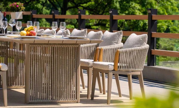 Outdoor dining area featuring a modern rectangular table with rope-detailed base and cushioned dining chairs with wooden frames