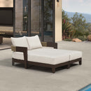 Outdoor double daybed with beige cushions, pillows, dark aluminum frame on poolside patio