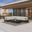 Black L-shaped patio conversation set with beige cushions and coffee table on an outdoor patio.