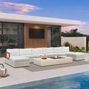 White U-shaped patio conversation set with white cushions, ottoman, and aluminum frame couch by a pool.