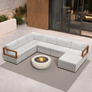 White U-shaped patio conversation set with wood accents and ottomans surrounding a stone fire pit on a grey rug.